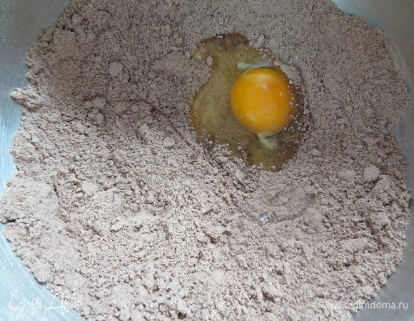 Ввести охлажденное масло и при помощи насадки «весло» на самой медленной скорости перемешать до состояния мелкой крошки. Ввести ванильный экстракт и яйцо. 