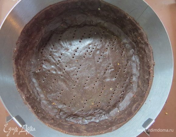 Холодное тесто раскатать толщиной 2–3 мм между двумя листами пергамента. Уложить в разъемную форму или кольцо диаметром 22 см, сформировать бортики, часто наколоть вилкой. Убрать в морозильник на час и более.