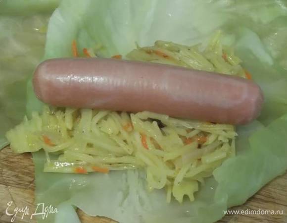 На капустный лист выложить 2 ст. л. начинки и сверху сосиску.
