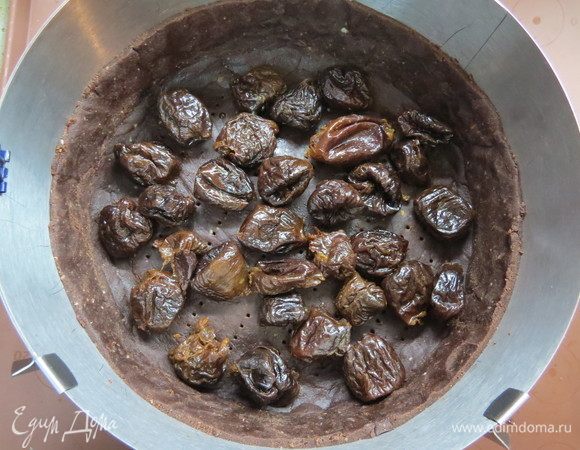 Вынимаем замороженную песочную основу, равномерно распределяем чернослив.