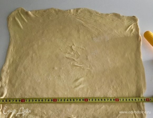 Теперь руки поместите под тесто ладошками вниз, пальцы слегка согните. И тяните тыльной стороной ладони тесто по направлению от центра к краям. Когда центр теста хорошо растянется, переходим к краям. Пальчиками необходимо растягивать тесто участок за участком, перемещаясь по всей его поверхности. Таким образом должен получиться прямоугольник размером 50/35 см.