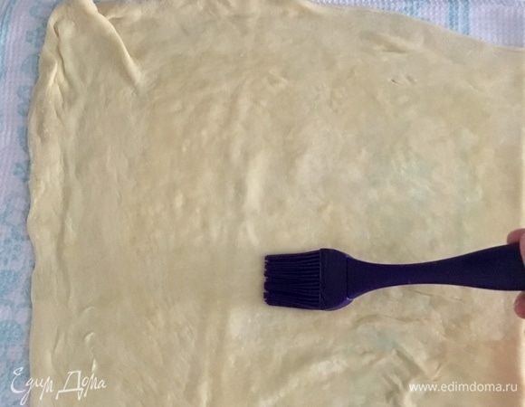 Пока я тянула тесто, я аккуратно перенесла его на чистое кухонное полотенце. Теперь тесто смазать маслом.