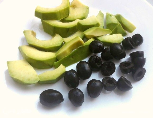 Оливки разрезать пополам, авокадо нарезать дольками.