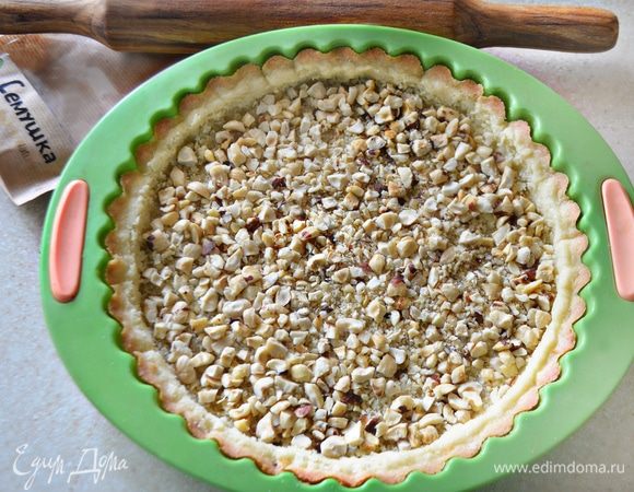 Фундук порубите в крупную крошку, для этого я поместила орехи в целлофановый пакет и несколько раз прошлась скалкой. Равномерно распределите орехи поверх основы для тарта.