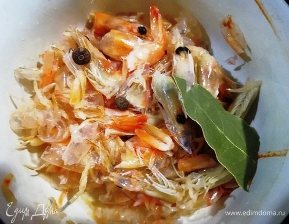 В небольшую кастрюльку кладем панцири креветок, лавровый лист, соль и перец. Заливаем 1 стаканом холодной воды и варим бульон 20 минут.