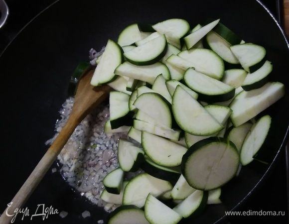 В глубокой сковороде разогреть масло и пассеровать лук (подойдет и репчатый) и чеснок. Добавить цукини, нарезанные на полудольки. Обжарить в течение нескольких минут. Поставить вариться рис. 