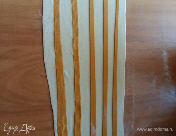 Нарезать ножом для пиццы оранжевое тесто на тонкие полосочки, выложить произвольно на белое.