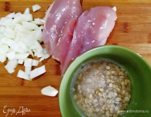 Куриную грудку очистим от кожи и вырежем киль. Овсяные хлопья ТМ «Националь» зальем кипятком и оставим на 10 минут для набухания. Лук и чеснок порежем.