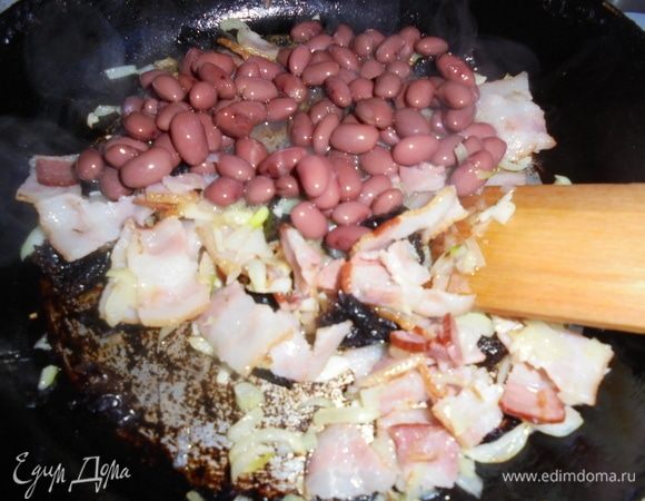 Добавьте чеснок. С фасоли ТМ «Фрау Марта» слейте жидкость и добавьте фасоль в сковороду.