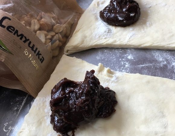 Основание прямоугольника немного посыпать мукой и выложить по столовой ложке шоколадного сгущенного молока.