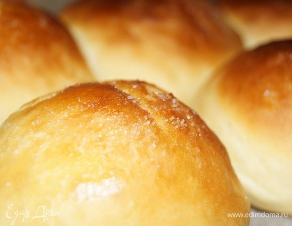 После того, как наши колобки увеличились дважды в объеме, ставим их в разогретый до 220°С жарочный шкаф на 20–30 минут (до образования румяной (не горелой) корочки). Время зависит от характеристик вашего жарочного шкафа. Я смазываю булочки сливочным маслом, можно растительным, сразу после того, как вынула их из духовки. Иногда сверху перед выпечкой посыпаю сахаром, можно кунжутом. Когда вы изъяли противень с булочками из духовки, накройте его чистым полотенцем и дайте булочкам немного остыть, чтобы они легче отставали от бумаги. Затем аккуратно выкладывайте эту красоту на блюдо. Хранить такую выпечку желательно в закрытой посуде. Она останется мягкой и вкусной до тех пор, пока вы ее не съедите. Но поверьте, такие булочки не залеживаются долго.