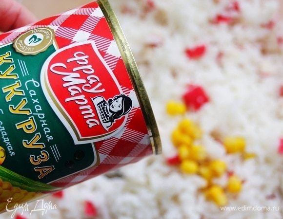 В глубокую кастрюлю или контейнер высыпаем отваренный рис, нарезанные крабовые палочки. Сливаем из консервированной кукурузы ТМ «Фрау Марта» воду и добавляем к остальным ингредиентам. 