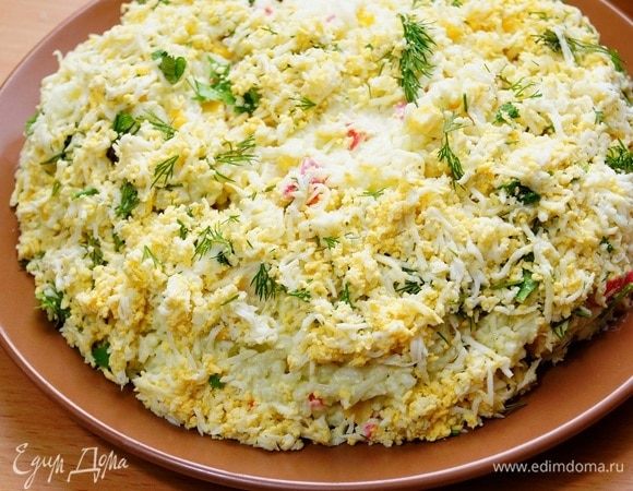 Выкладываем салат на плоскую тарелку. Натертые яйца с зеленью выкладываем по бокам нашего салата, как это показано на фото.