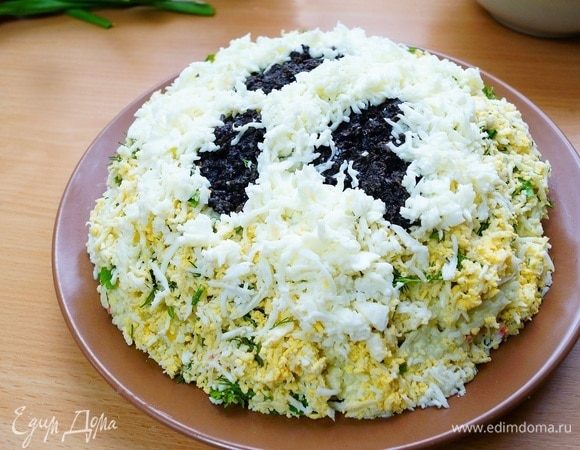 У оставшихся двух яиц отделяем белок от желтка. Белок натираем на мелкой терке и выкладываем поверх нашего салата, формирую таким образом подтаявший снег. 