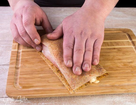 Положите отбитое филе на половину листа MAGGI®, закройте второй половиной и прижмите рукой.