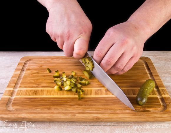 Нарежьте кубиками огурцы.