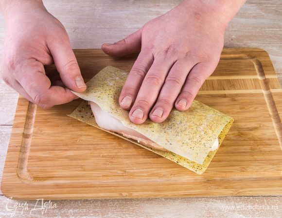 Положите отбитое филе на половину листа MAGGI®, закройте второй половиной и прижмите рукой.