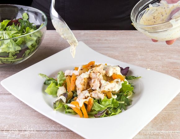 Выложите салатные листья на тарелку, а на них выложите курицу с курагой и изюмом и полейте все заправкой.