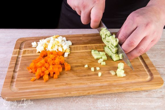 Морковь отварите в кожуре в подсоленной воде 30 минут, яйца — 15 минут. Мытые огурцы, очищенную морковь и яйца нарежьте кубиками. Один желток оставьте для заправки.