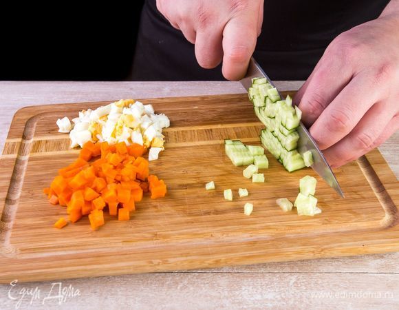 Морковь отварите в кожуре в подсоленной воде 30 минут, яйца — 15 минут. Мытые огурцы, очищенную морковь и яйца нарежьте кубиками. Один желток оставьте для заправки.
