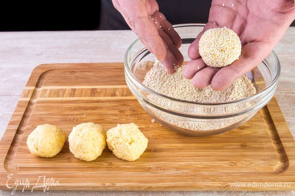 Смочите руки в холодной воде, чтобы тесто не прилипало к рукам, и скатайте из него небольшие шарики. Каждый шарик обваляйте в семенах кунжута.