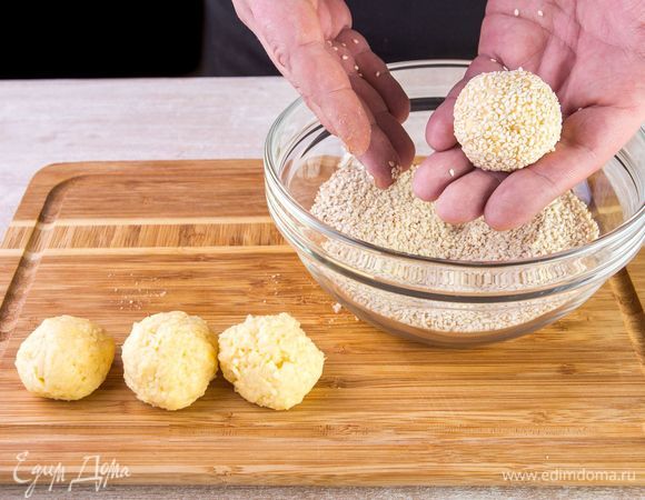 Смочите руки в холодной воде, чтобы тесто не прилипало к рукам, и скатайте из него небольшие шарики. Каждый шарик обваляйте в семенах кунжута.