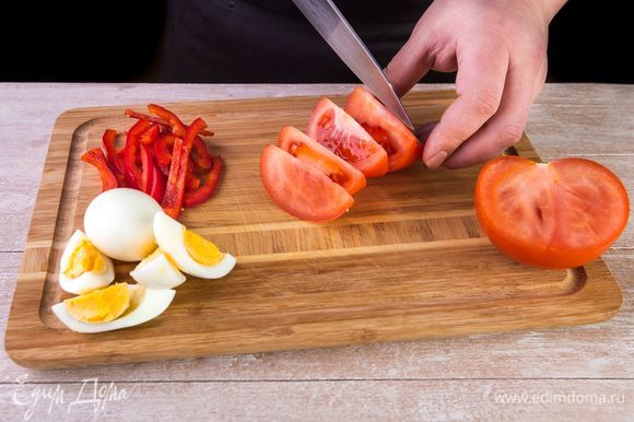 Нарежьте помидоры дольками. Отварите два яйца, очистите от скорлупы и нарежьте дольками. Сладкий перец очистите от семян и нарежьте тонкой соломкой.