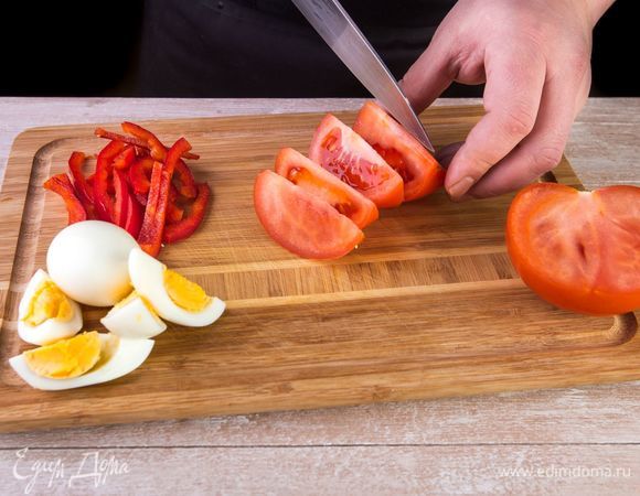 Нарежьте помидоры дольками. Отварите два яйца, очистите от скорлупы и нарежьте дольками. Сладкий перец очистите от семян и нарежьте тонкой соломкой.  