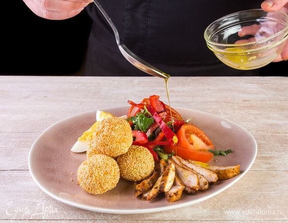 На порционную тарелку горкой выложите листья салата и овощи. На салат выложите остывшие сырные шарики. Готовим заправку для салата. В миске смешиваем сок лимона, оливковое масло и пропущенный через пресс чеснок. Взбиваем все венчиком до состояния эмульсии.