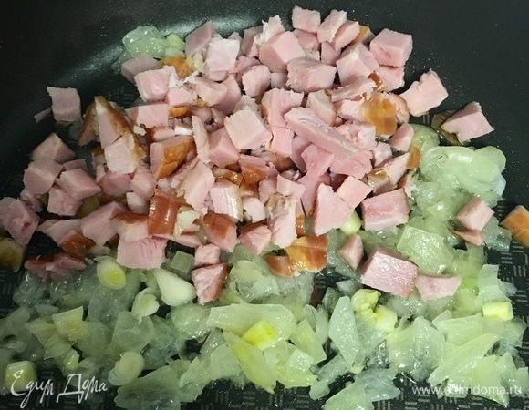 Теперь приготовим первую начинку. Здесь все элементарно. Порубить мелко луковицу. В сковороде разогреть растительное масло и начать обжаривать лук. Тем временем кубиком нарезать ветчину. Можно взять бекон, фарш, да просто любое мясо. Как только лук станет прозрачным, ветчину добавить в сковороду и обжаривать вместе до готовности лука. Начинка готова. 