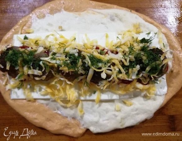 У нас есть время, оставшееся тесто раскатываем, укладываем на него пластинки плавленого сыра, кетчуп, мясные шарики, тертый сыр, зелень (или то, что есть в холодильнике). Формируем батон и укладываем его в форму для хлеба.