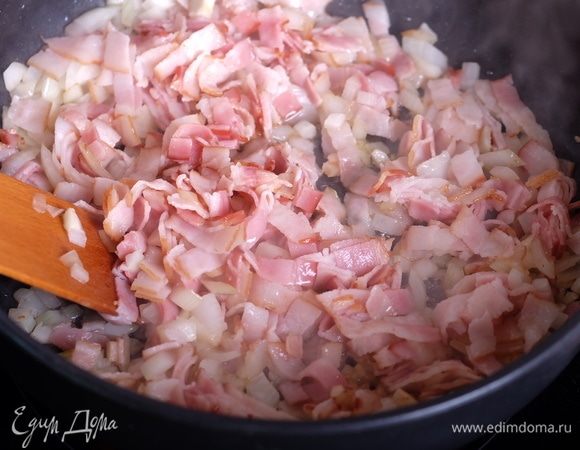 Бекон нарезать тонкими полосками, лук и чеснок мелко порубить. Обжарить лук, чеснок и бекон на той же сковороде примерно 5 минут, помешивая. Влить вино, жарить до полного выпаривания алкоголя.