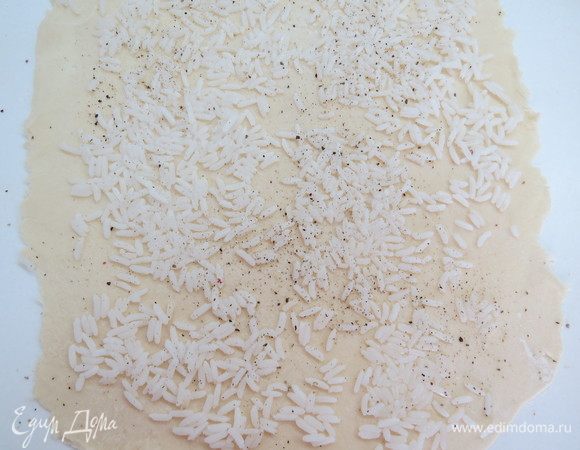 Тесто раскатываем в круг или прямоугольник. На раскатанное тесто выкладываем полуготовый рис, приправляем свежемолотым черным перцем.