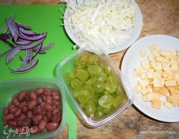 Сыр нарежьте небольшими кубиками. Виноград нарежьте на половинки, пекинскую капусту нарежьте тонкой соломкой. Лук нарежьте полукольцами.