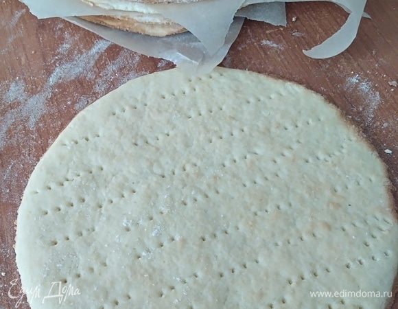 Разделить тесто на 10 коржей. Раскатать их, посыпая скалку и стол мукой. Вырезать по форме круги диаметром 18–20 см. Наколоть коржи вилкой. Выпекать по 3–5 минут в разогретой духовке. Остудить.