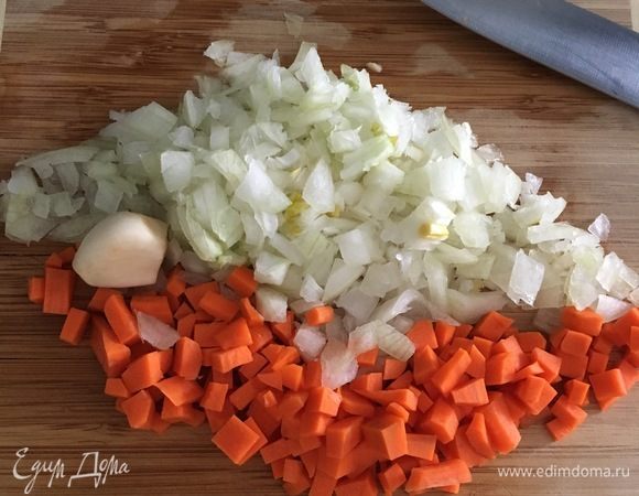 Подготовим овощи для мясного хлеба. Почистим 1 среднего размера луковицу, морковь и зубчик чеснока. Мелким кубиком нарезать лук и морковь. Зубчик чеснока раздавить тыльной стороной ножа и измельчить.