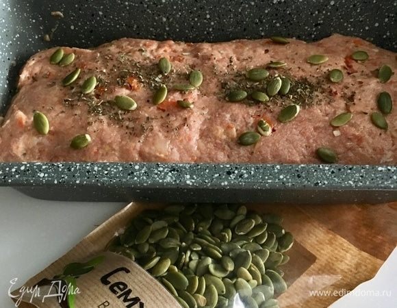 Закрываем хлебушек фаршем. Посыпать щепоткой базилика и тыквенными семечками. Духовку заранее разогреть до 160°С. Форму с будущим мясным хлебом накрыть фольгой. В духовку поставить поддон с водой и отправить хлебушек выпекаться на водяной бане на 1 час 50 мин. Последние 10 мин. раскрыть хлебушек и подставить под гриль. В процессе приготовления образуется сок-жирок. Его необходимо будет слить.