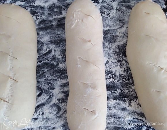 Подошедшие багеты. Сделать надрезы острым ножом. Если вы любите мягкую корочку, то сейчас самое время смазать заготовки кисточкой, смоченной в воде. Поставить выпекать на 25 минут.