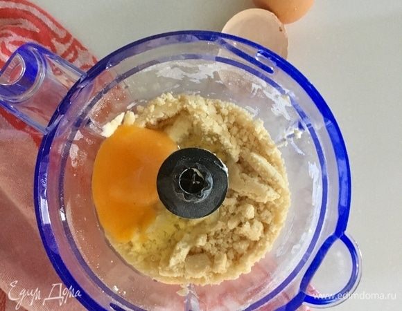 Начать пробивать блендером. Когда мука с маслом превратится в крошки, разбить одно яйцо. Перемешать.