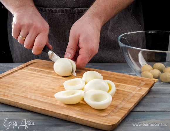 Куриные яйца отварите, охладите, очистите и разрежьте их вдоль пополам. Затем аккуратно выньте желтки и положите в миску. Белки накройте пищевой пленкой и поставьте в холодильник.