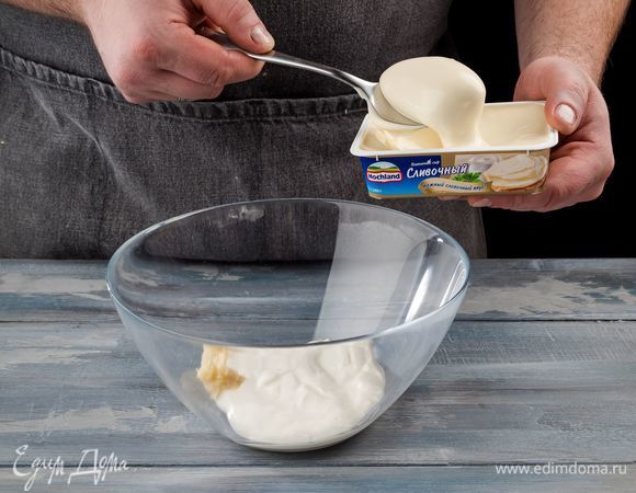 Приготовьте начинку для рулетиков. Для этого плавленый сыр Hochland сливочный соедините с давленым чесноком и сметаной. Все хорошо перемешайте.