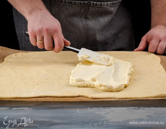 Разделите подошедшее тесто на две части, раскатайте их в прямоугольники и равномерно распределите по всей поверхности теста творожную начинку. 