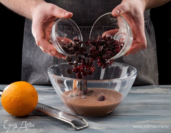 Сушеную клюкву промойте, обсушите и добавьте ее в подошедшее тесто. Также добавьте шоколадные капли и цедру апельсина. Еще раз замесите тесто и снова оставьте на подъем на час.