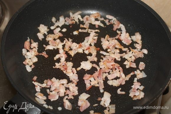 На сухой сковороде обжарьте бекон, вытопите из него жир и переложите бекон в другую посуду. Если вытопившегося жира мало, добавьте кусочек сливочного масла или любого растительного.
