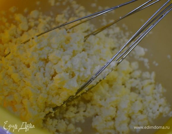 Добавьте творог. В отдельной емкости смешайте муку, соль, соду.