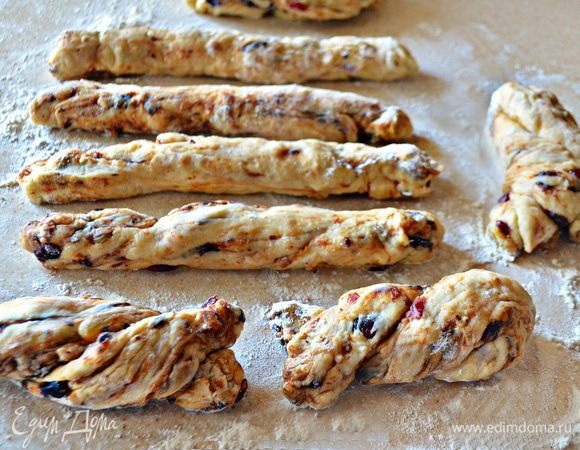 Переложить поднявшееся тесто на посыпанный мукой стол, тщательно обмять, накрыть полотенцем и дать подойти еще раз. После разделить на небольшие кусочки, скатать жгутики и сложить пополам, скрутив кончики 2–3 раза.