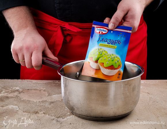 Приготовьте зеленую глазурь Dr. Oetker. Опустите пакетик с глазурью в горячую воду на 3–5 минут. Выложите его на полотенце и слегка надавите, чтобы сделать текстуру глазури более однородной.