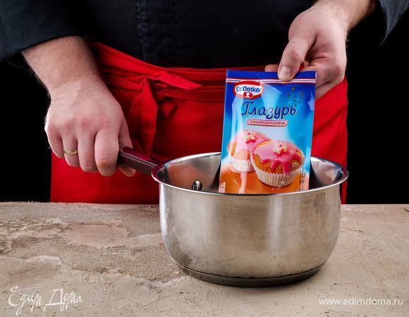 Приготовьте розовую глазурь Dr. Oetker. Опустите пакетик с глазурью в горячую воду на 3–5 минут. Выложите его на полотенце и слегка надавите, чтобы сделать текстуру глазури более однородной.