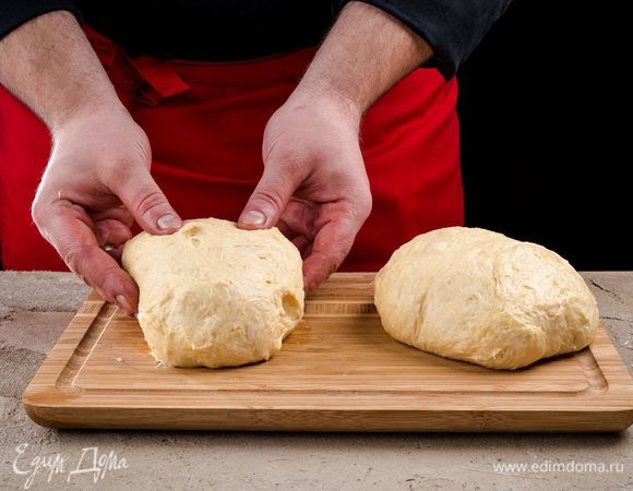 Подошедшее тесто разделите на 2 части, каждую скатайте в шар.