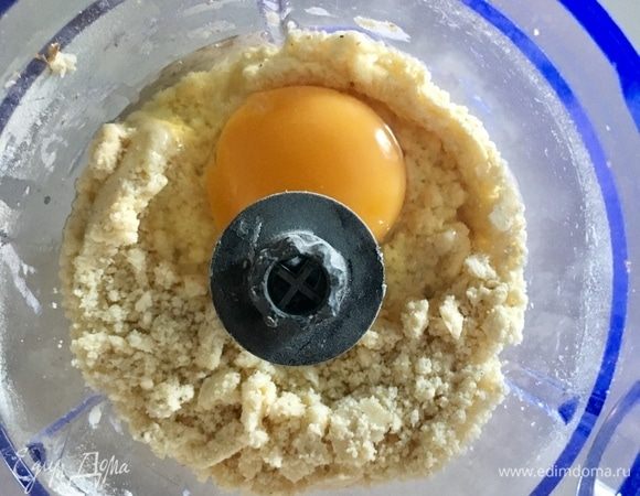 Как только получили консистенцию крошки, вбиваем одно яйцо. Снова перемешиваем. Начинает формироваться на ноже блендера нежное песочное тесто.